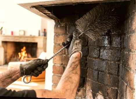 Technician inspecting and brushing a firebox interior in a Newark home