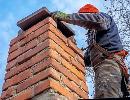 Mason setting stone atop fresh brick coursework