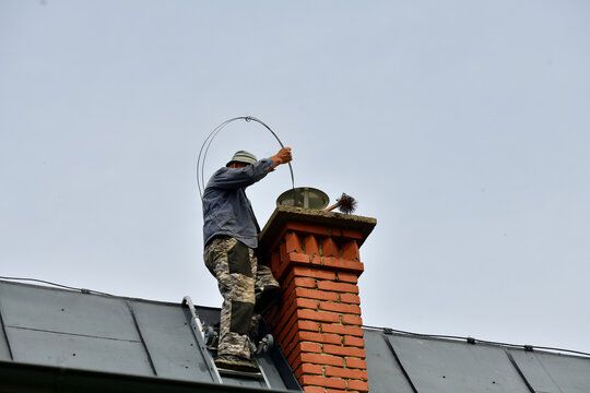 Technician feeding a flexible line down a chimney flue